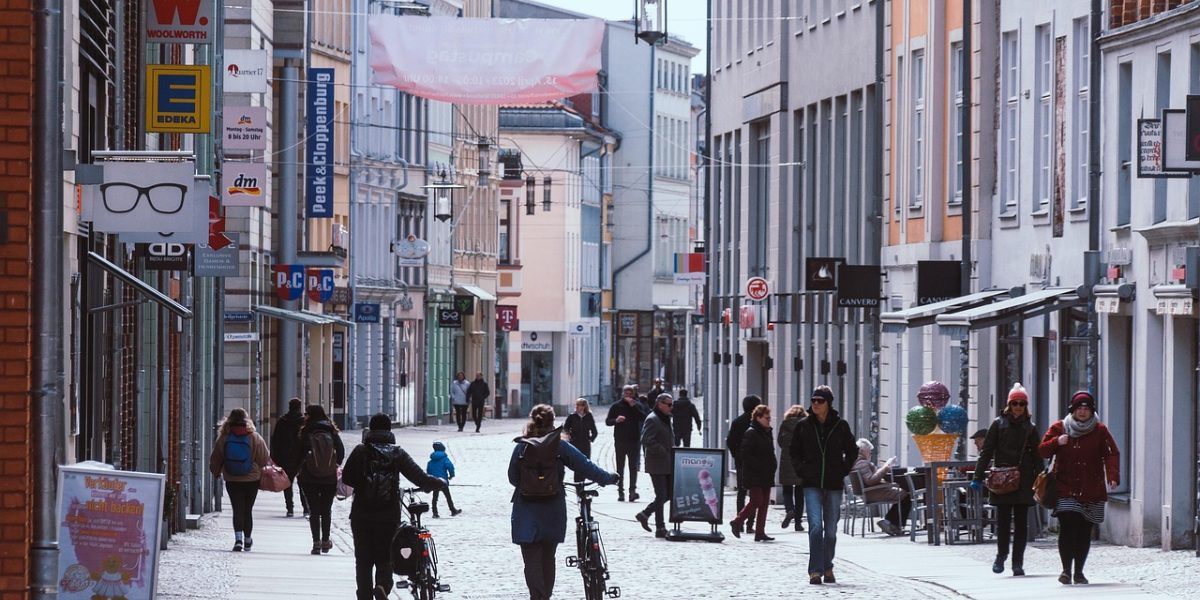 欧洲城市街道上商店橱窗的欧元价签特写，行人虚化背景，傍晚暖色路灯映在玻璃上，呈现真实购物比价场景